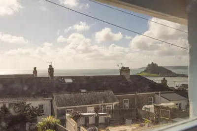 a view from a window of houses and the ocean at School Cottage, Marazion in Marazion