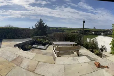 a patio with a picnic table and a bench at Rivermead Beach House -Modern beach house with indoor pool in Treknow