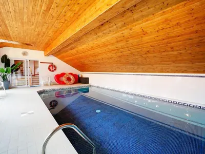 an indoor swimming pool with a wooden ceiling at Rivermead Beach House -Modern beach house with indoor pool in Treknow