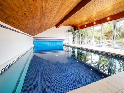 a swimming pool in a house with a wooden ceiling at Rivermead Beach House -Modern beach house with indoor pool in Treknow