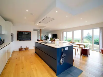 a large kitchen with a large island in the middle at Rivermead Beach House -Modern beach house with indoor pool in Treknow