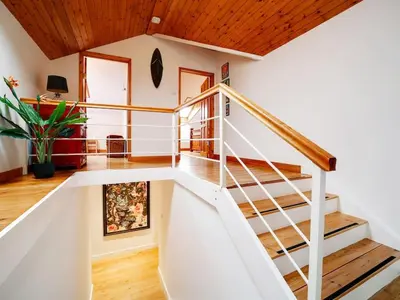 a white staircase in a home with wooden ceilings at Rivermead Beach House -Modern beach house with indoor pool in Treknow