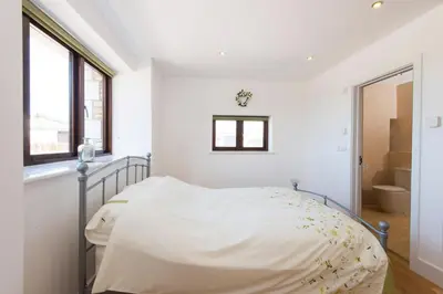 a white bedroom with a bed and a window at Trippet Cottage in Saint Breward
