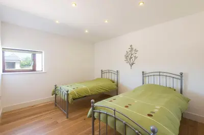 two beds in a room with white walls at Trippet Cottage in Saint Breward