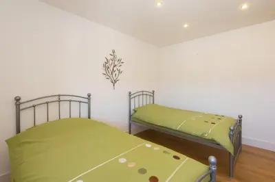 two beds in a room with green sheets at Trippet Cottage in Saint Breward