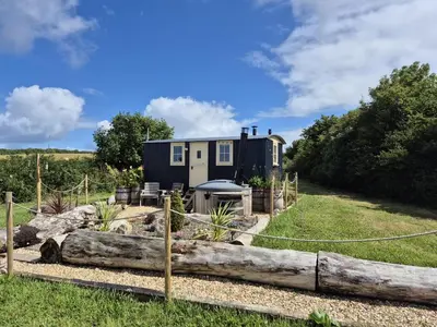 a tiny house in a garden with a log at Shepherds haven hut Near Padstow in Saint Issey