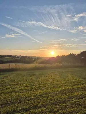 a field with the sun setting in the horizon at Shepherds haven hut Near Padstow in Saint Issey