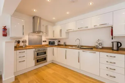 a kitchen with white cabinets and stainless steel appliances at Jubilee Cottage - Cwc75016 in Saint Breward