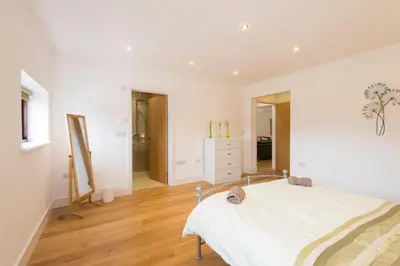 a bedroom with a white bed and wooden floors at Jubilee Cottage - Cwc75016 in Saint Breward