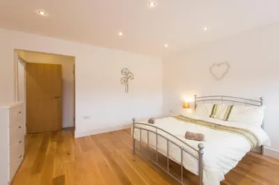 a bedroom with a bed with white walls and wooden floors at Jubilee Cottage - Cwc75016 in Saint Breward