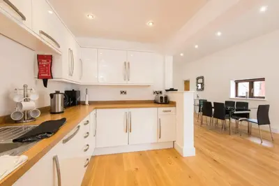 a kitchen with white cabinets and black chairs at Jubilee Cottage - Cwc75016 in Saint Breward