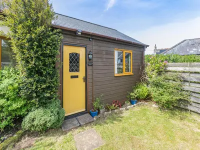 a small shed with a yellow door in a yard at Contention Barn in Perranporth