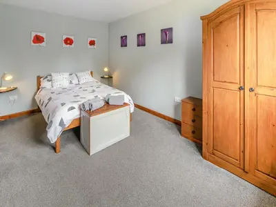 a bedroom with a bed and a wooden cabinet at Contention Barn in Perranporth
