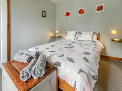 a bedroom with a bed with towels on it at Contention Barn in Perranporth
