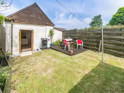 a small backyard with a table and two chairs at Contention Barn in Perranporth