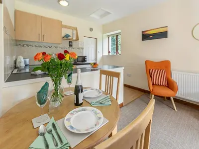 a kitchen and dining room with a table with flowers at Contention Barn in Perranporth