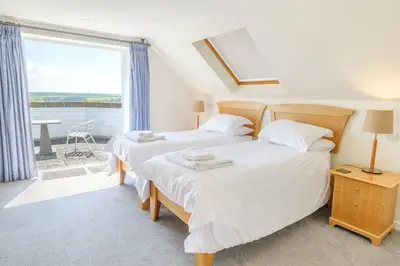 two beds in a room with a window at Flat 1 Mawgan Porth Golf Club in Mawgan Porth