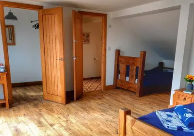 a room with a bed and a open door at Heart of Kernow Holidays in Bugle