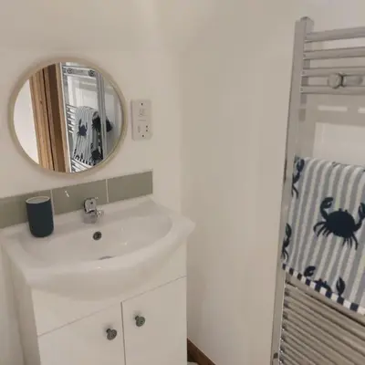 a white bathroom with a sink and a mirror at Heart of Kernow Holidays in Bugle