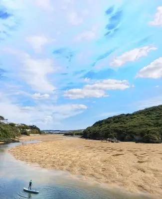 a person on a surfboard in the water on a beach at Heart of Kernow Holidays in Bugle