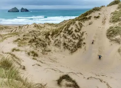 two people walking on a sandy beach near the ocean at Heart of Kernow Holidays in Bugle