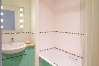 a white bathroom with a sink and a mirror at Flat 2 Mawgan Porth Golf Club in Mawgan Porth