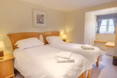 two beds in a room with white sheets at Flat 2 Mawgan Porth Golf Club in Mawgan Porth