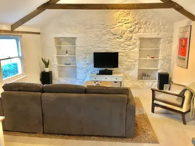 a living room with a brown couch and a tv at The Loft - Bright apartment centre St Ives sleep 4 in St Ives