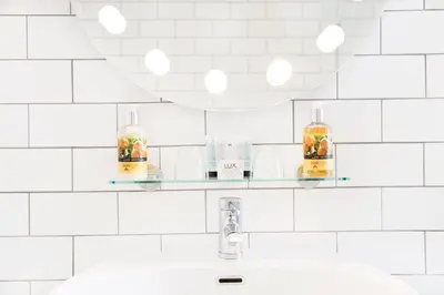 a white tiled bathroom with a sink and a mirror at The Lerryn in Falmouth