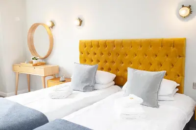 two beds with white sheets and a yellow headboard at The Lerryn in Falmouth