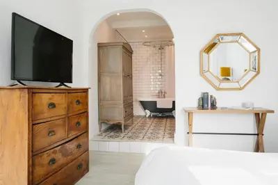 a bedroom with a tv on a dresser and a bathroom at Merchants Manor Spa in Falmouth