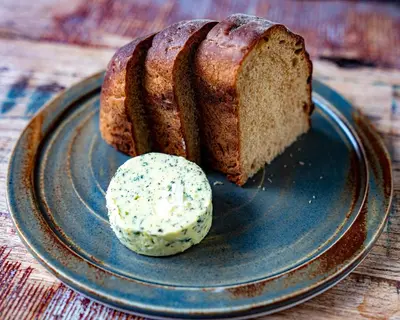 a piece of bread on a plate with a scoop of butter at Merchants Manor Spa in Falmouth