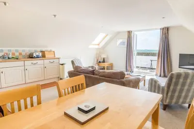 a living room with a table and chairs at Flat 3 Mawgan Porth Golf Club in Mawgan Porth