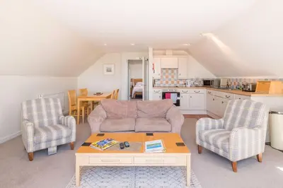 a living room with a couch and two chairs and a table at Flat 3 Mawgan Porth Golf Club in Mawgan Porth