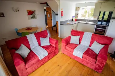 a living room with two red couches and a kitchen at Treworgie Barton - Myll in Bude