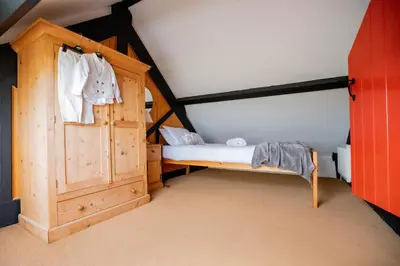 a small bedroom with a bed and a wooden door at Treworgie Barton - Myll in Bude