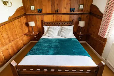 a bedroom with a large bed with wooden walls at Treworgie Barton - Myll in Bude