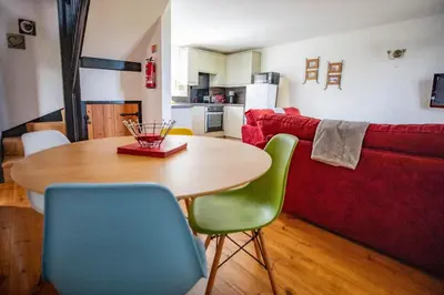 a living room with a table and a red couch at Treworgie Barton - Myll in Bude
