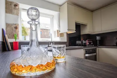 a glass decanter with two glasses on a kitchen counter at Treworgie Barton - Myll in Bude