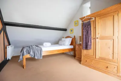 a small bedroom with a bed and a wooden cabinet at Treworgie Barton - Myll in Bude