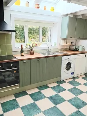 a kitchen with green cabinets and a checkered floor at The Barn in Penzance