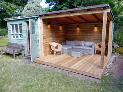a wooden pergola with a couch on a deck at The Barn in Penzance