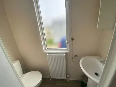 a bathroom with a toilet and a sink and a window at 11 Meadow View in Newquay