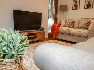 a living room with a couch and a flat screen tv at 1 Streamside in Looe