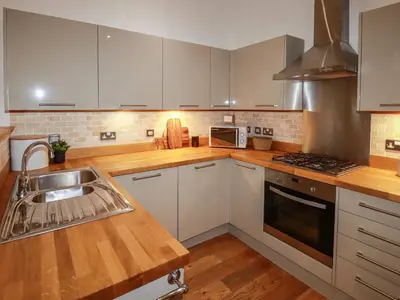 a kitchen with white cabinets and a sink at 1 Streamside in Looe