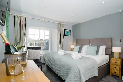 a bedroom with a bed and a table with a bottle of wine at St Agnes Hotel in St. Agnes