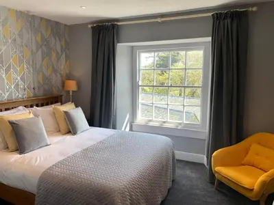a bedroom with a bed and a window and a chair at St Agnes Hotel in St. Agnes