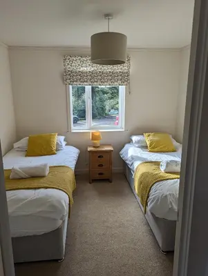 two twin beds in a room with a window at Two Bedroom Lodge In The Country - Restaurant Bar Onsite in Liskeard