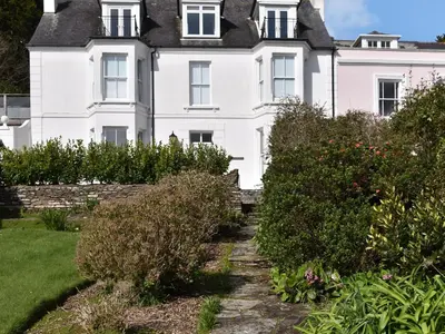 a white house with bushes in front of it at Bessborough in Saint Mawes