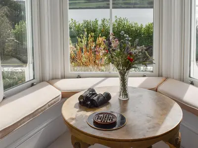 a living room with a table and a vase of flowers at Bessborough in Saint Mawes